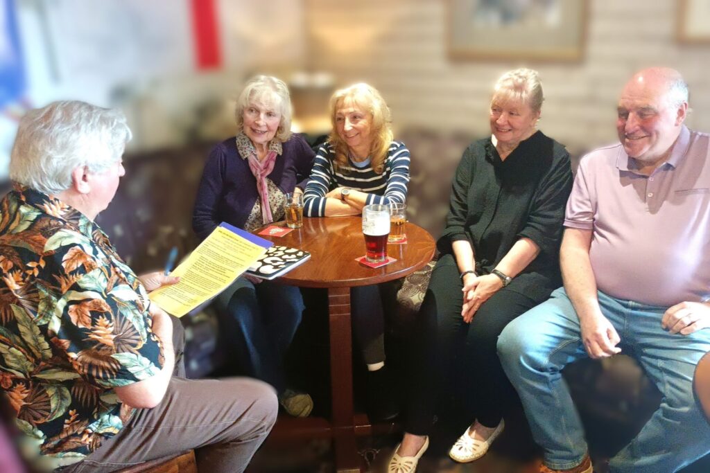 Giggles, Gigs and Grins : group members discussing activities around a table.