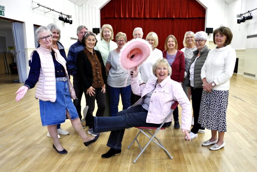 Line Dancing teacher sitting at the front surrounded by her group
