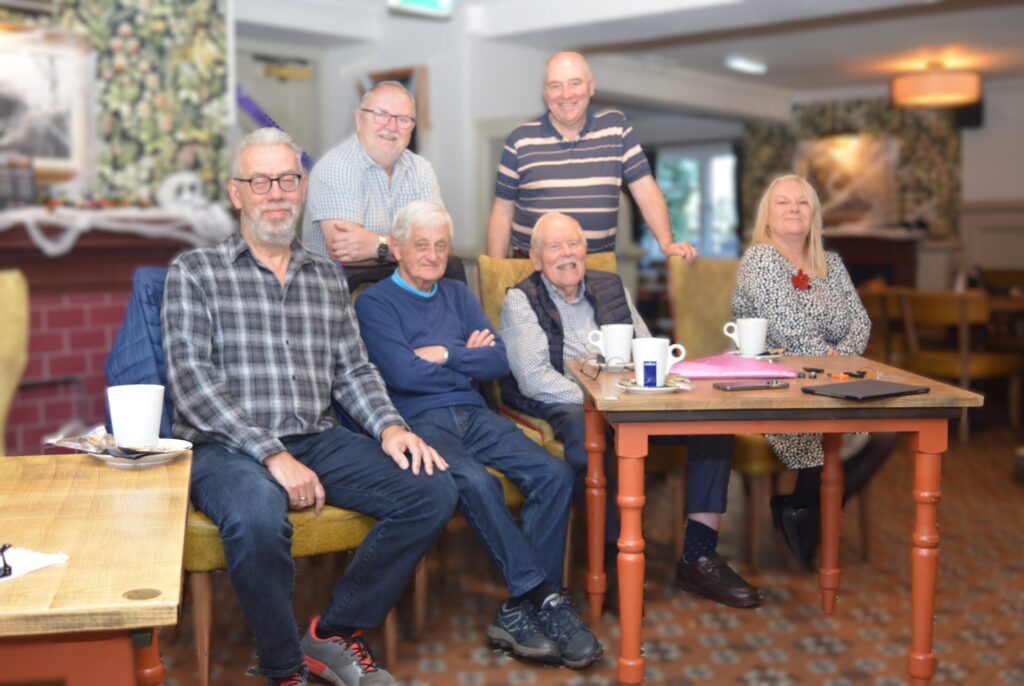 Photography group members facing the camera for a group portrait at their monthly meeting.
