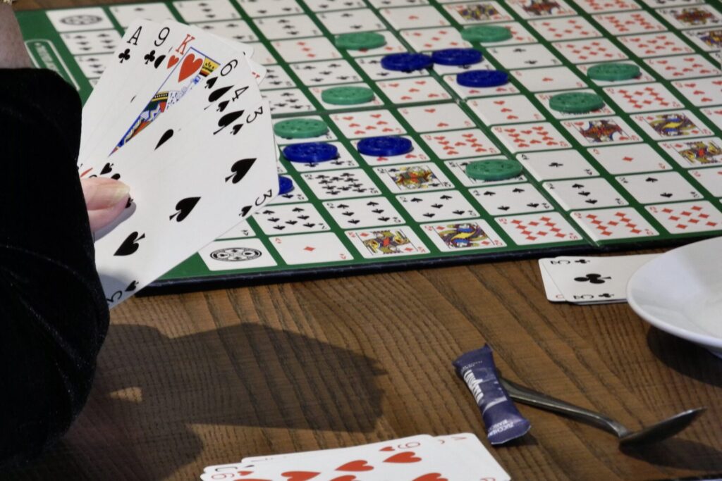 The Sequence board with some counters placed on it and a player's hand holding cards before deciding what to play.hand